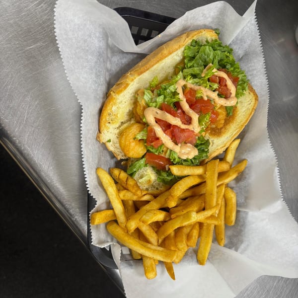 A Snazzy's Hot Wings shrimp po'boy with lettuce, tomatoes, and sauce, served with fries.