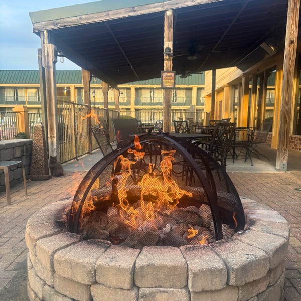 A cozy outdoor patio at Snazzy's Hot Wings with a lit fire pit and seating.