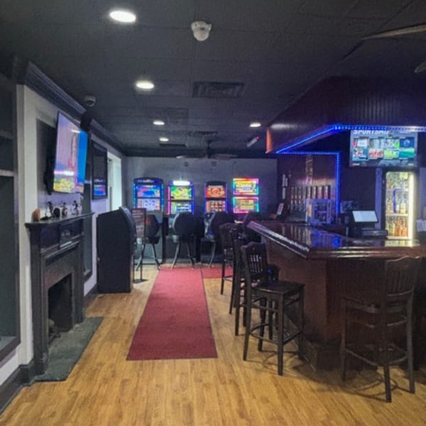 Interior of Snazzy's Hot Wings, featuring a bar with stools, gaming machines, and a red carpet.