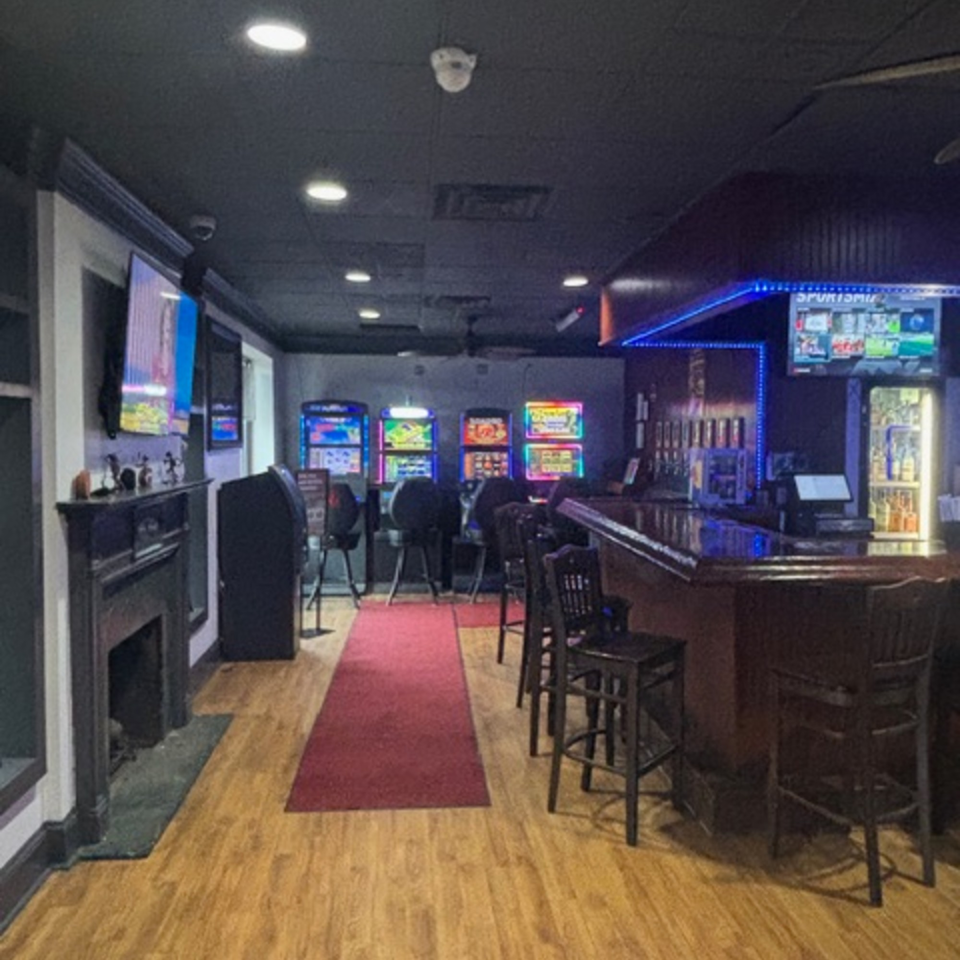 Interior of Snazzy's Hot Wings, featuring a bar with stools, gaming machines, and a red carpet.